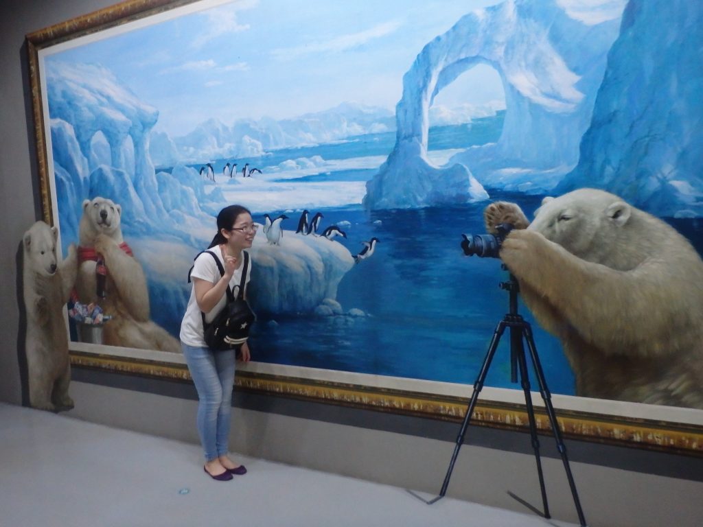 お母さんクマが小熊と一般客にカメラで写真を撮っているように見えるトリックアート