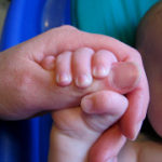 父親の親指を五つの指で握る赤ん坊