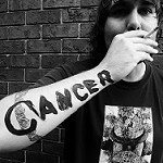 タバコを吸う利き腕にCancer（ガン）と書かれています