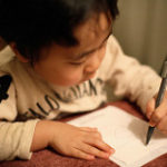 左手で手紙を書く子供