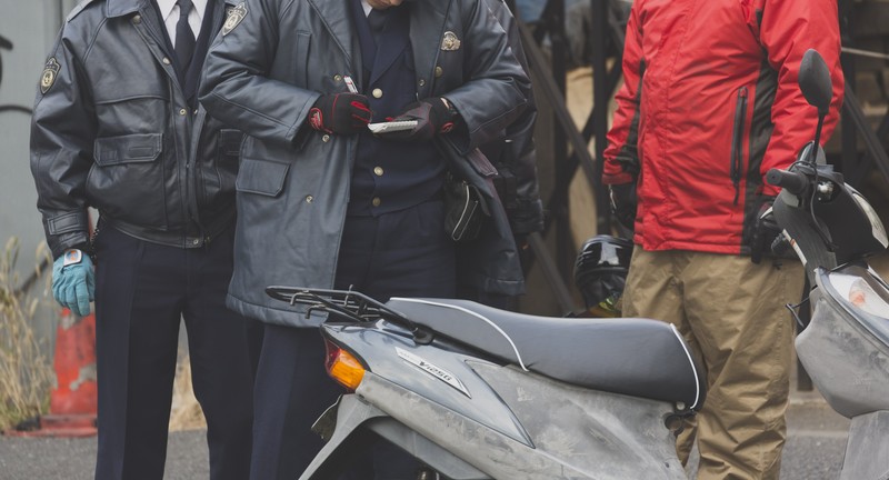 不審なバイク運転手に事情聴衆する警察官