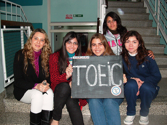 TOEICと書かれた黒板ボードを掲げる女学生たち