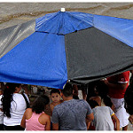 巨大な傘の下で雨をしのぐ人々