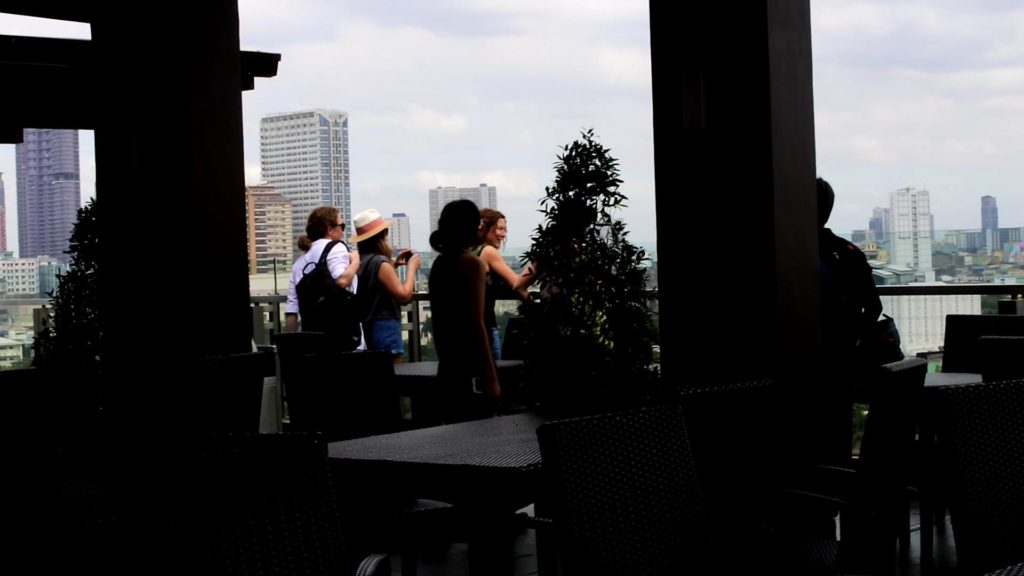 ホテル屋上でマニラ市の360度パノラマを楽しむ欧米人観光客たち